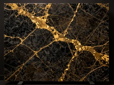 Close-up macro detail of polished dark gold and black marble slab with rich illuminated veins on a dark reflective backdrop