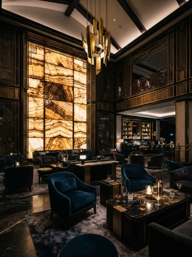 Dramatic architectural interior of a luxury hotel grand lounge with backlit onyx panels, gold architectural accents, and high-end modern seating under dark moody lighting